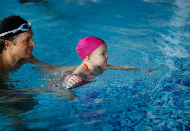 Happy Kid Toddler Learns To Swim With Coach In The Pool,